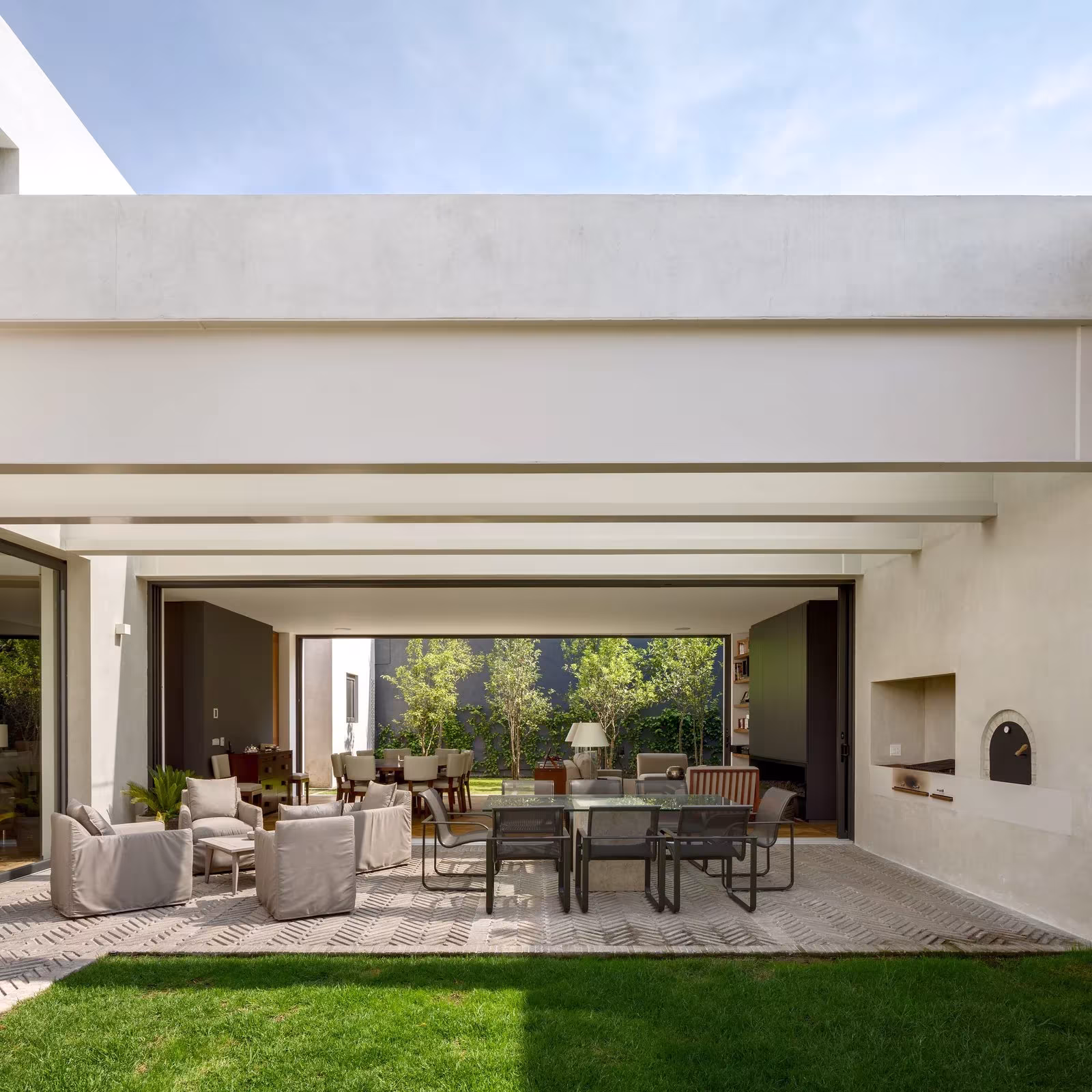 Porche abierto con comedor y sala de estar al borde del jardín de la Casa Jardín 58, en México