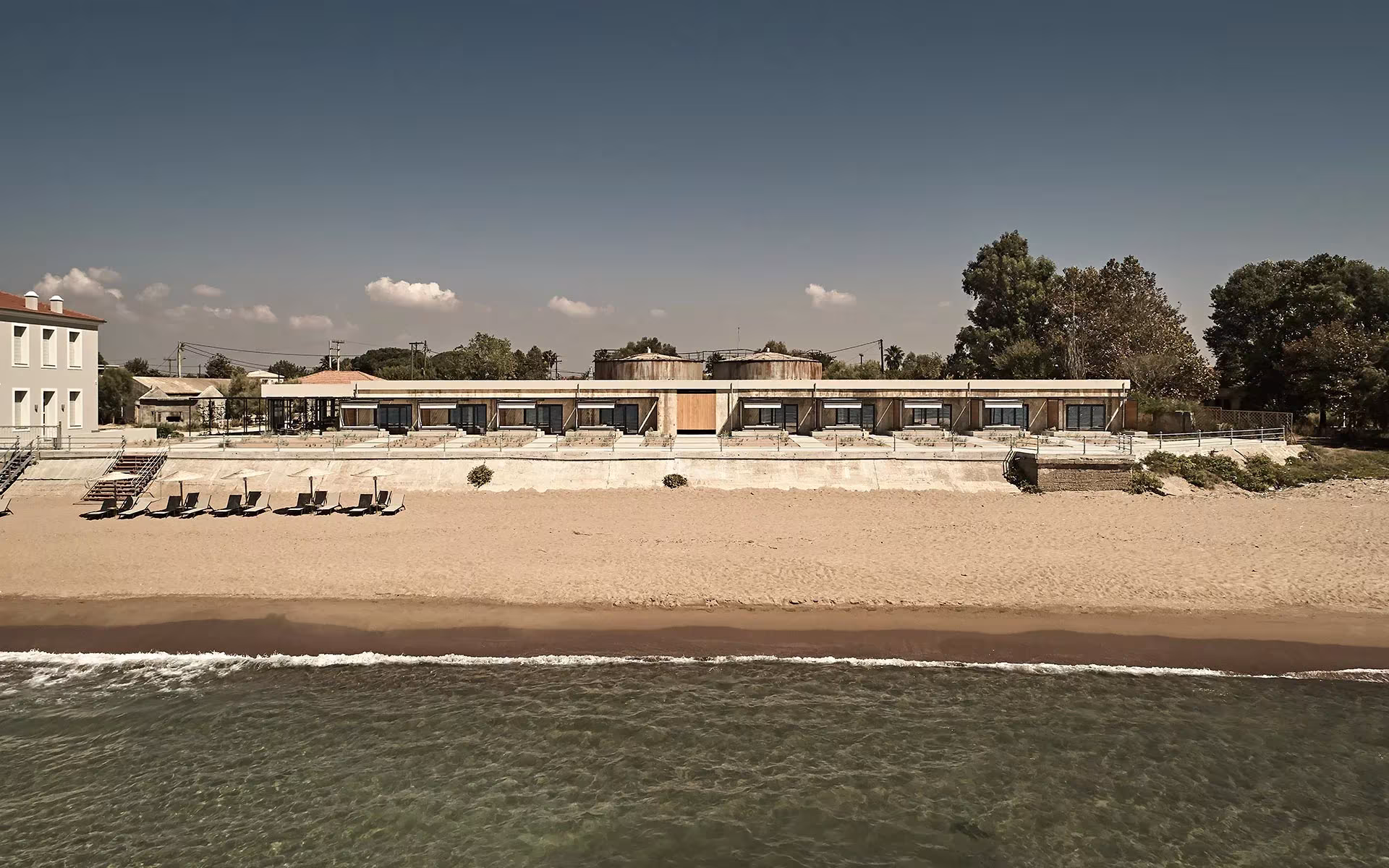 Dexamenes Seaside Hotel de K-Studio visto desde el mar, con la playa y las tumbonas en el Peloponeso