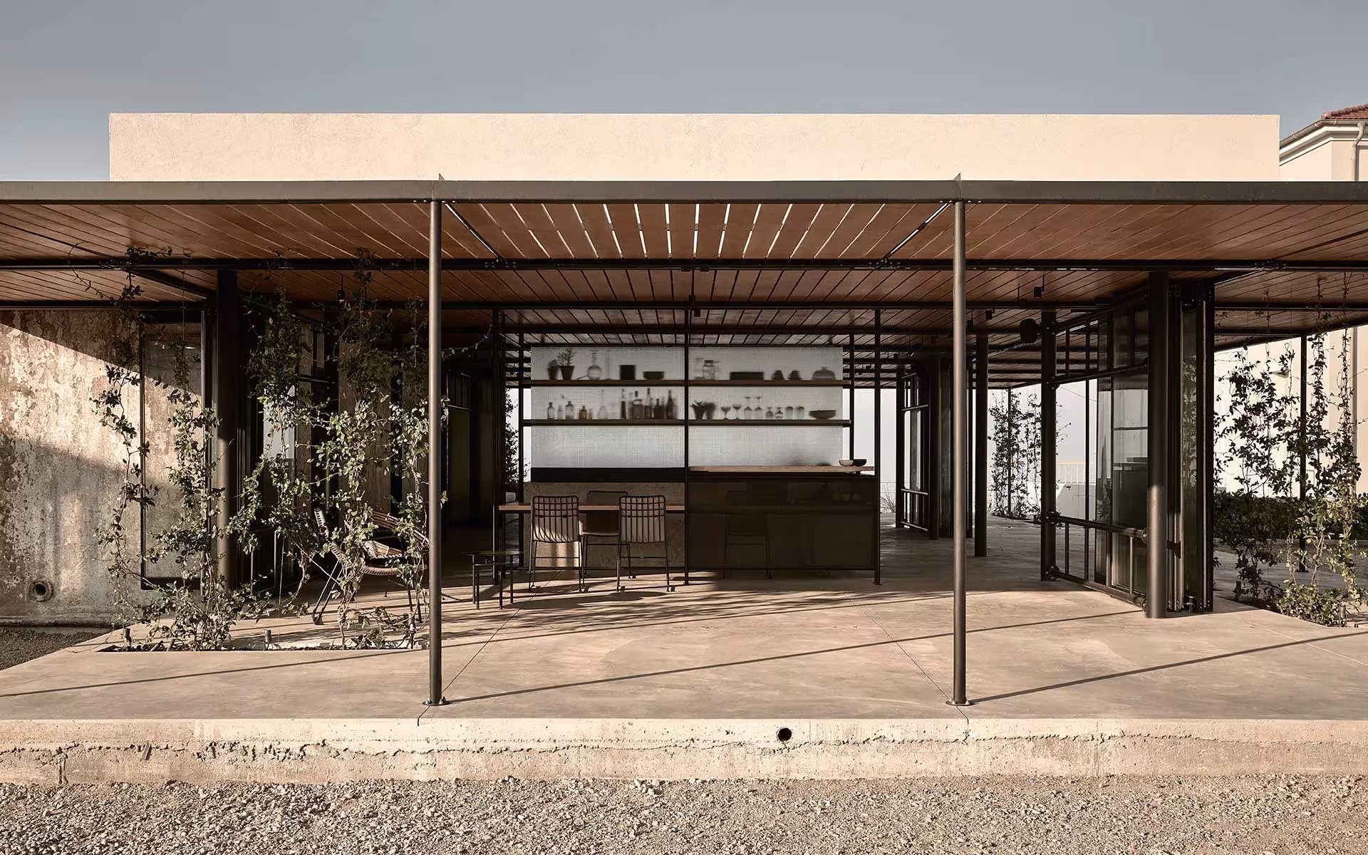 Pabellón de cristal con pérgola de madera y estructura de acero negro en el Dexamenes Seaside Hotel