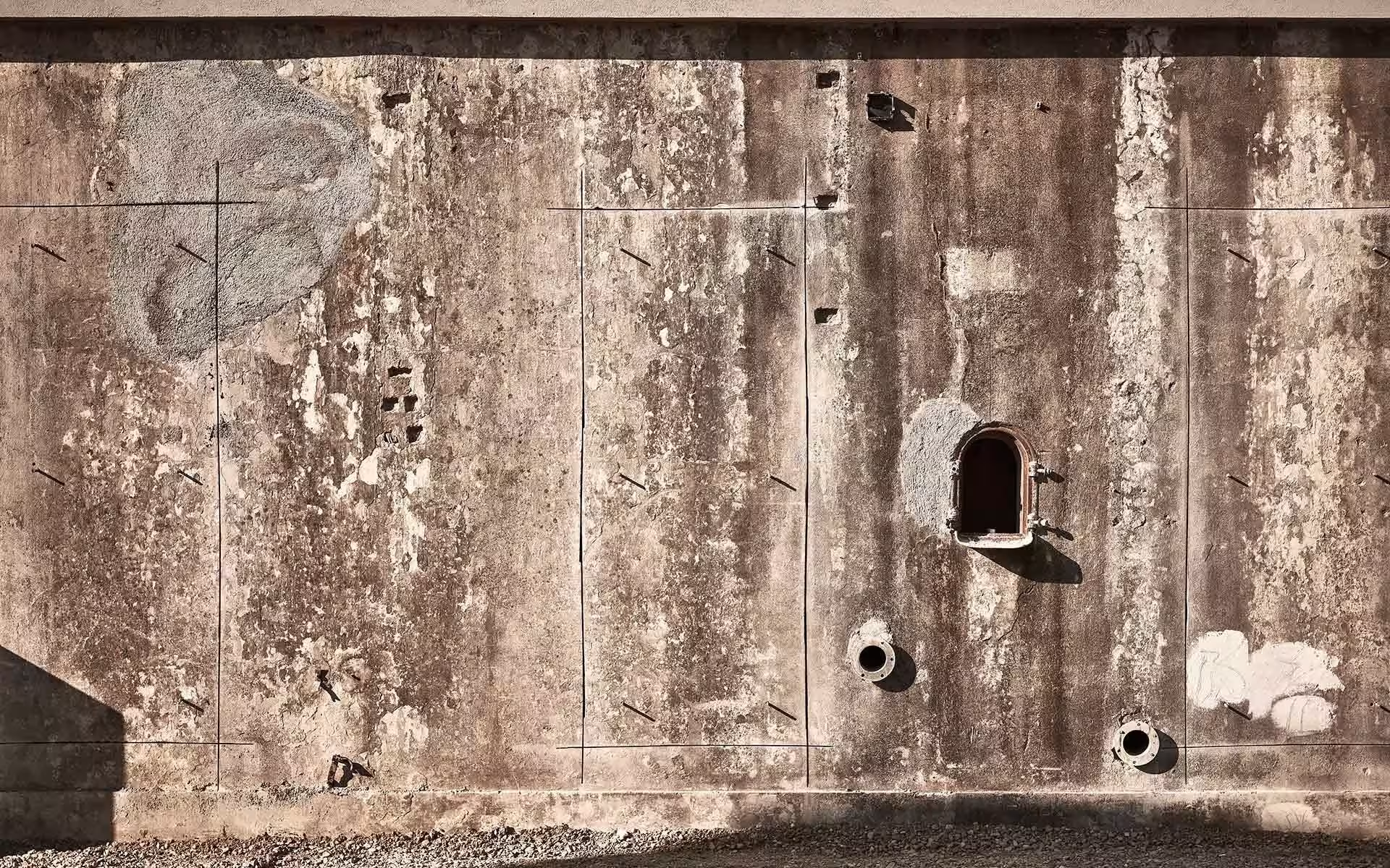 Muro de hormigón envejecido y manchado, resto de la fábrica de vino, en el Dexamenes Seaside Hotel