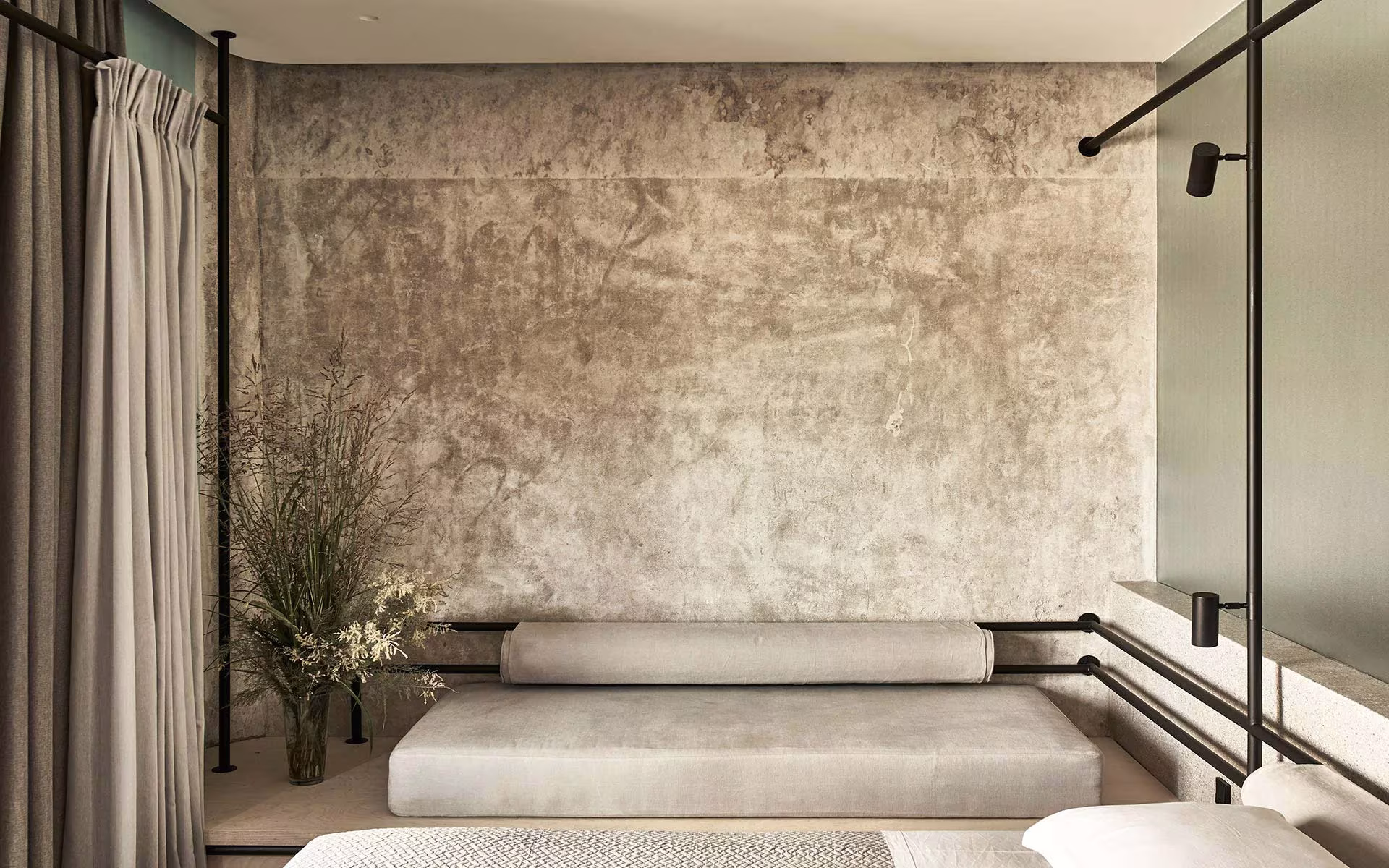 Habitación del Dexamenes Seaside Hotel con cortina, banco corrido y muro de hormigón envejecido