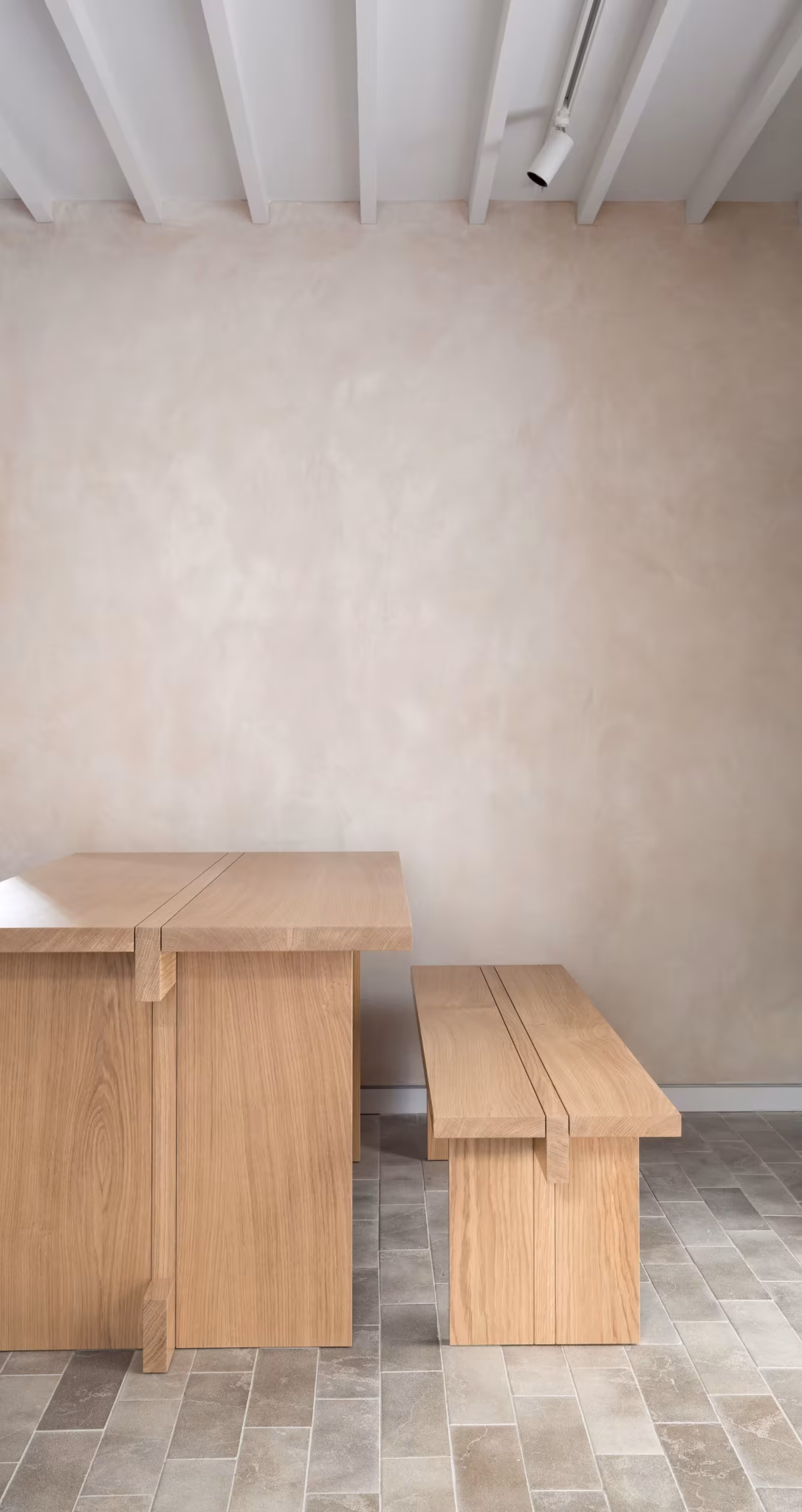 Mesa y banco de roble en un rincón de pared de cal y suelo cerámico en el Porteous Studio de Edimburgo