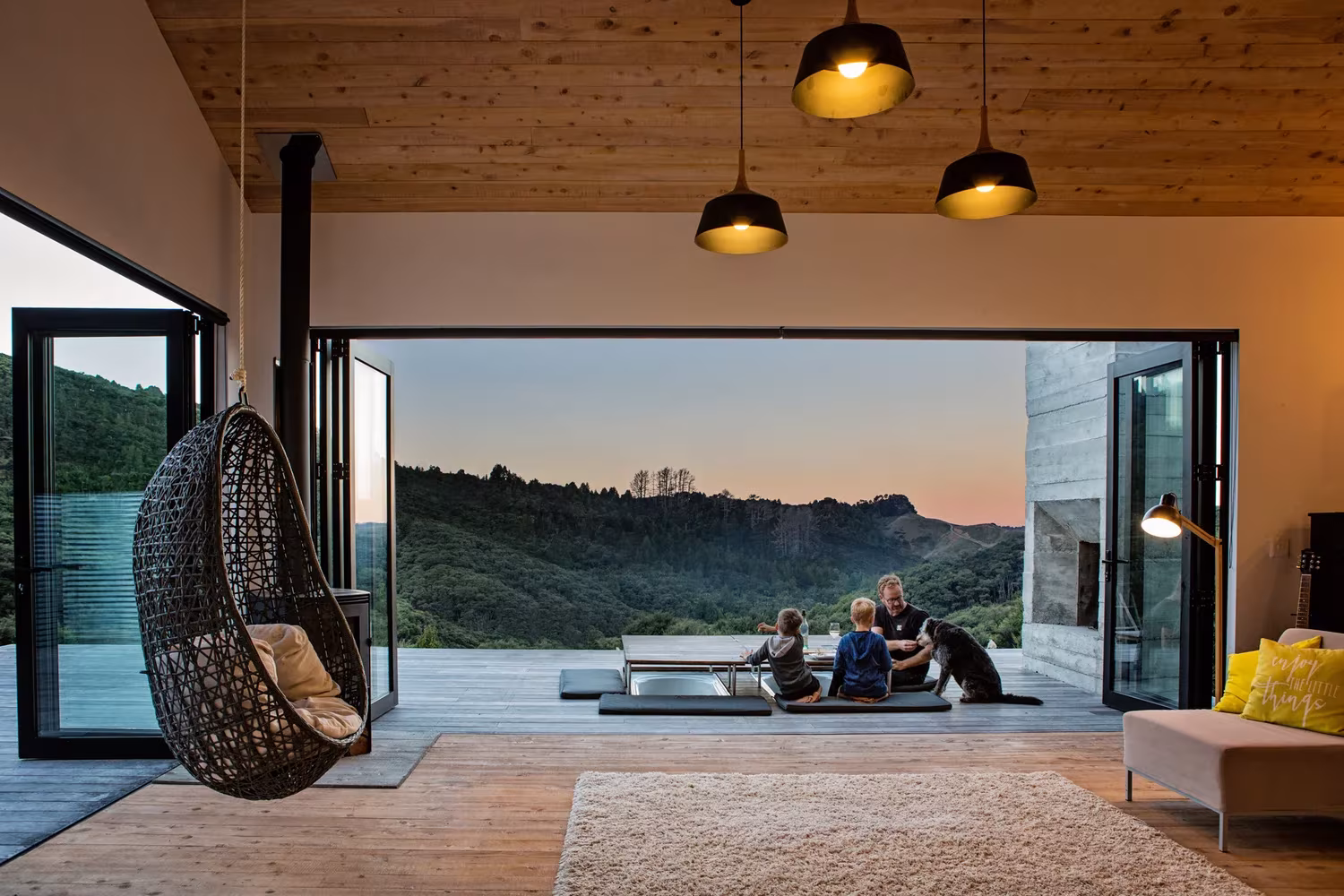 Salón abierto al valle con sillón colgante y lámparas negras en la Back Country House de LTD