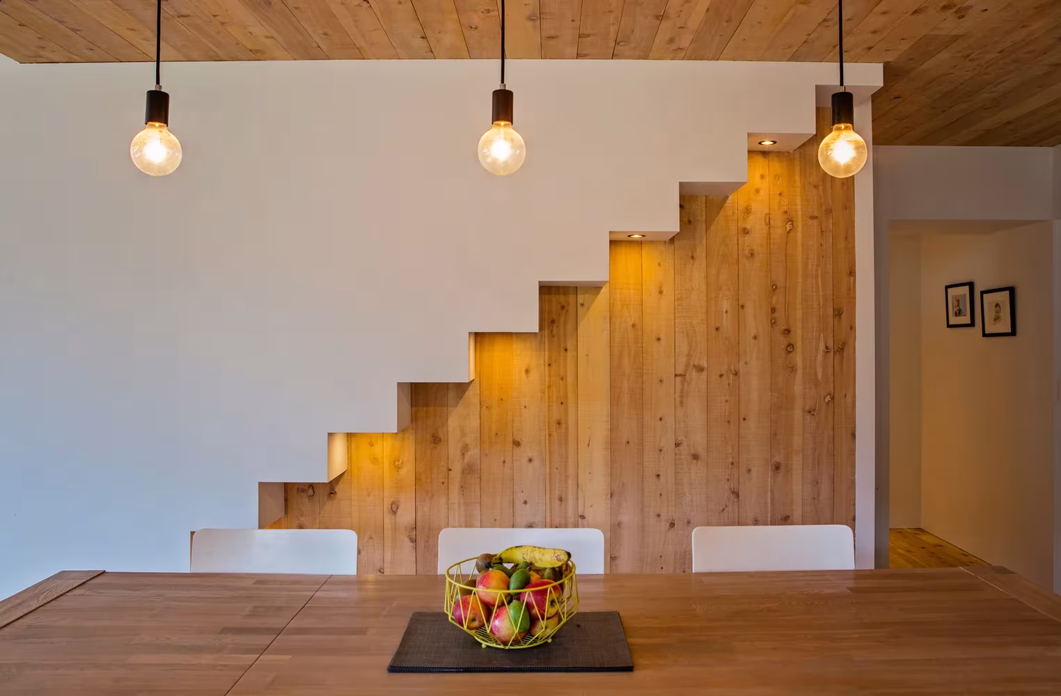 Escalera de peldaños volados con luces y mesa de comedor de madera en la Back Country House de LTD