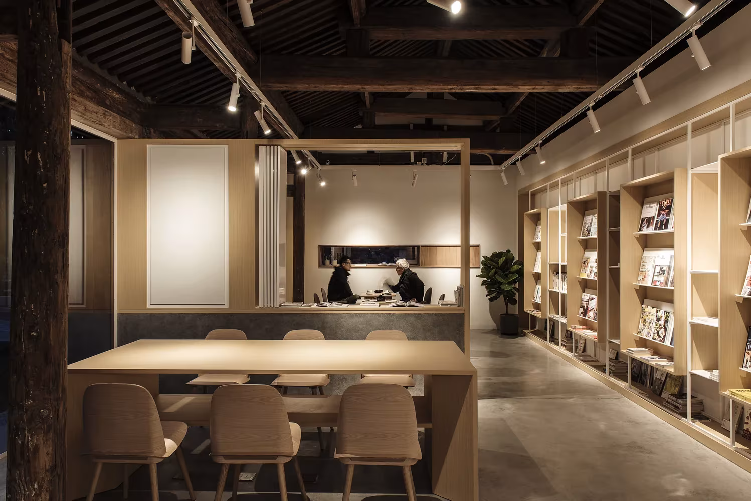 Sala de lectura del club Spring Whispers con vigas vistas, estanterías de madera y mesa corrida, en Pekín