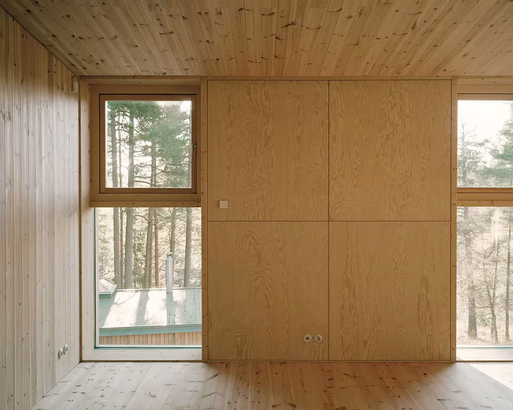 Habitación de tablas de pino con ventanas laterales y panel de madera central en la Villa Idun-Lee