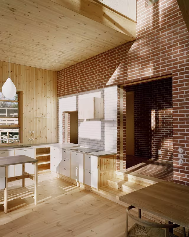 Cocina de la Villa Idun-Lee con paneles de pino, muro de ladrillo visto y peldaños de madera