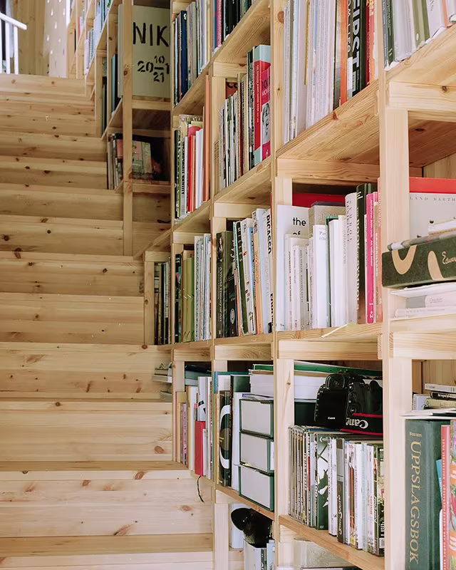 Escalera de madera con estantería de libros a pie de peldaño en la Villa Idun-Lee de Anton Kolbe