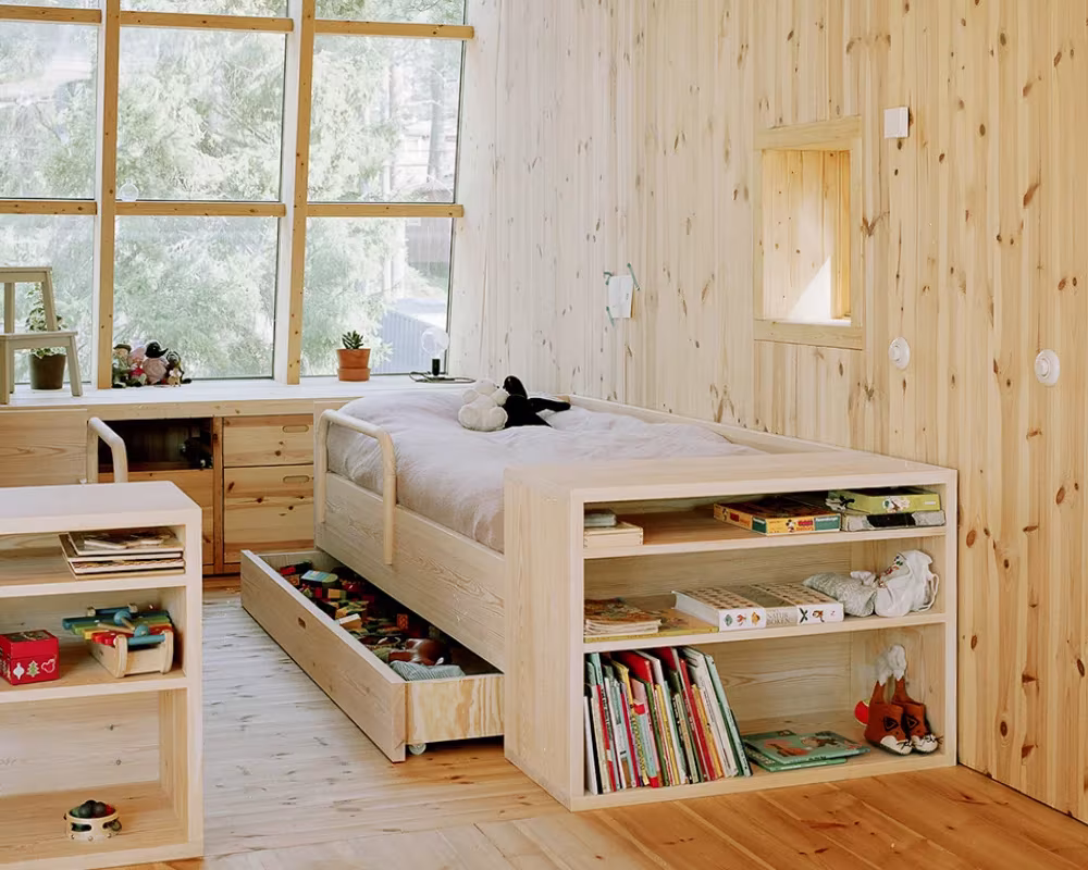 Dormitorio infantil de pino con cama con cajones, estantes y ventanal al bosque en la Villa Idun-Lee