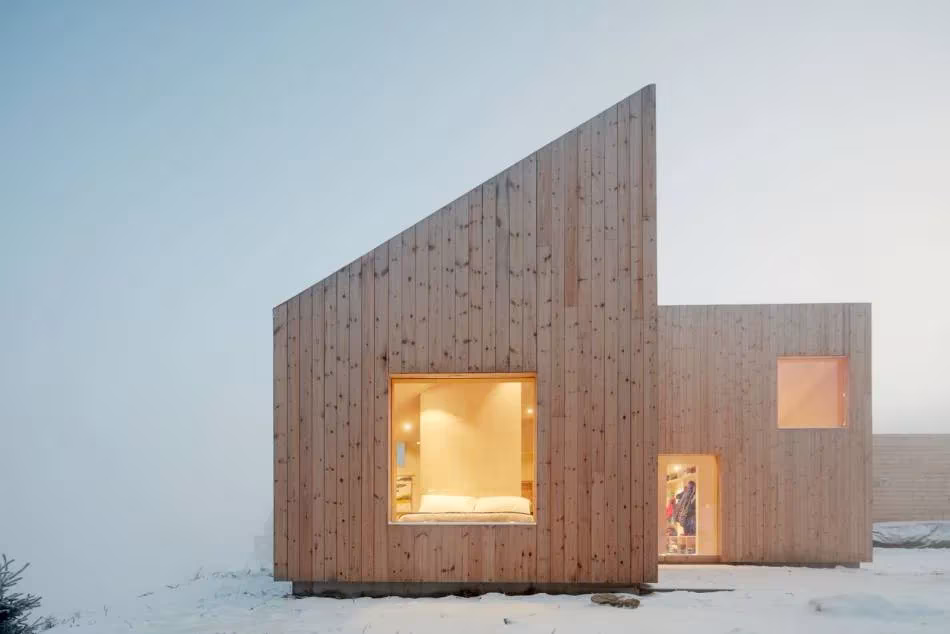 Fachada de tablas de madera con ventana cuadrada iluminada entre la niebla en la Mylla Hytte, en Noruega