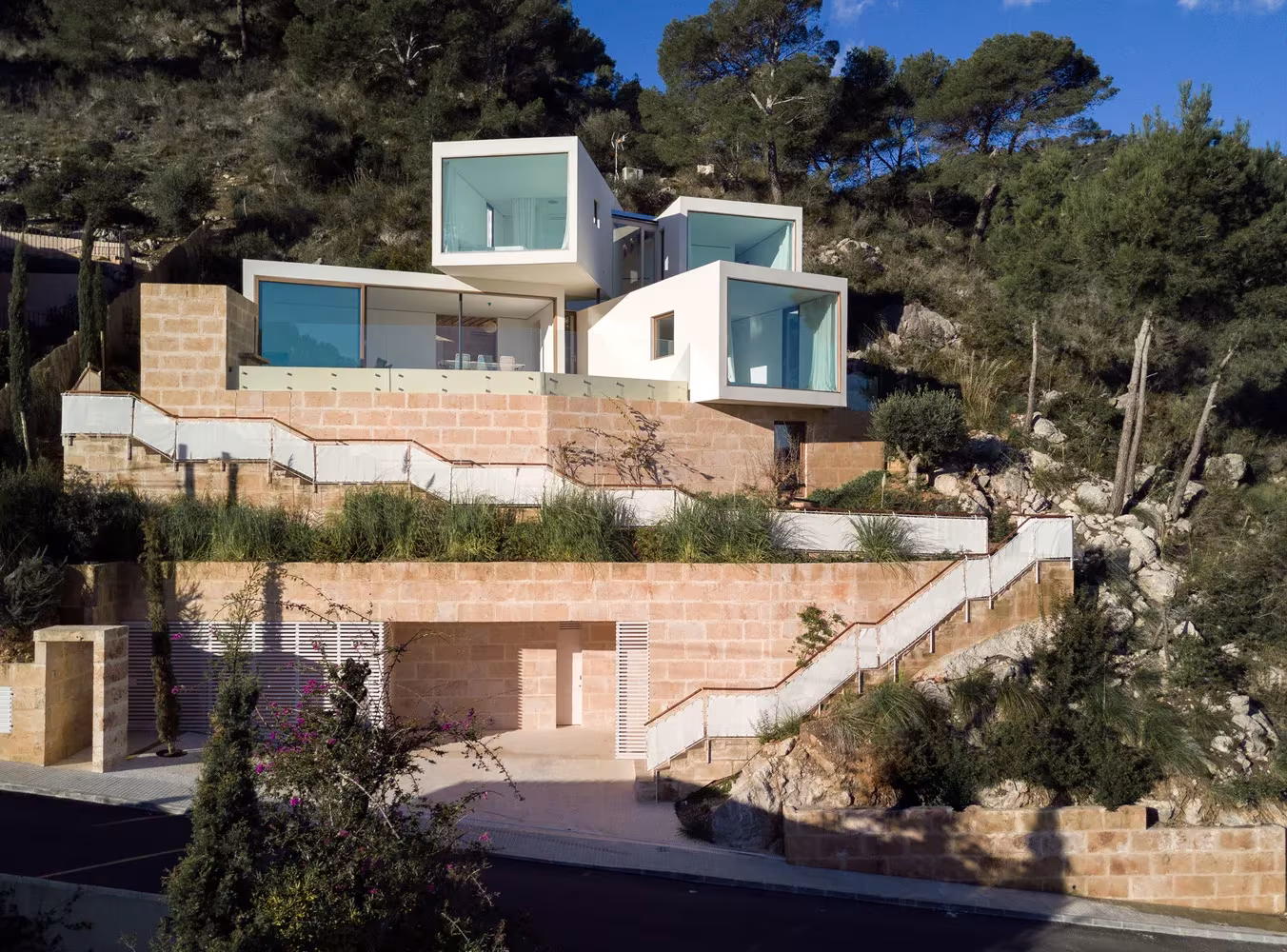Casa Can Canyís con sus prismas blancos apilados sobre los bancales de piedra de la ladera, en Canyamel