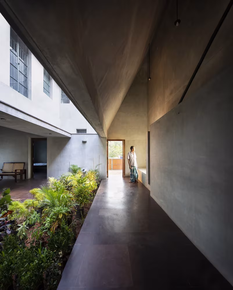 Pasillo de hormigón cubierto junto al jardín interior de Court House, con luz cenital rasante, Chennai