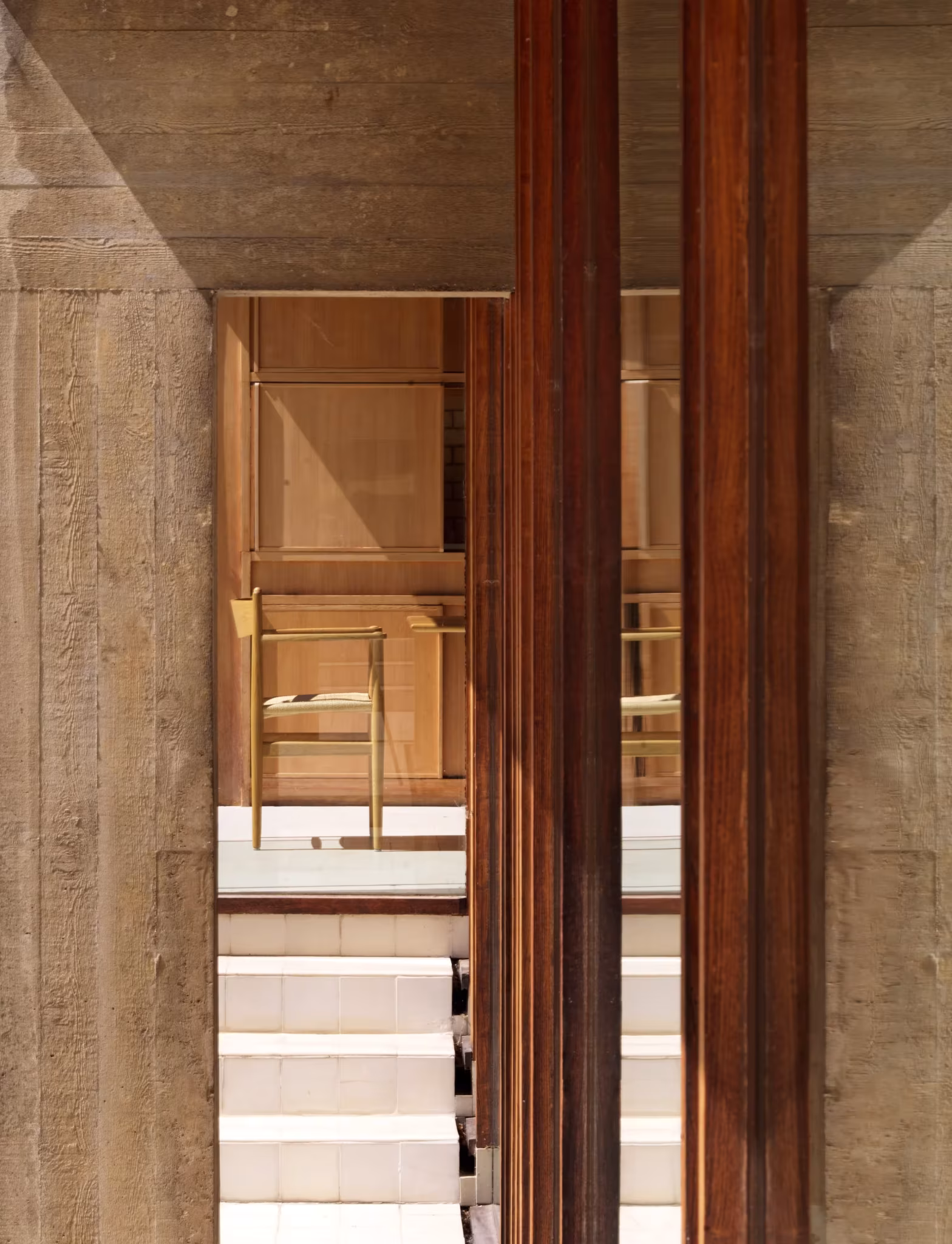 Pilares de acero corten y muro de hormigón visto enmarcan la entrada de la Ahm House de Jørn Utzon