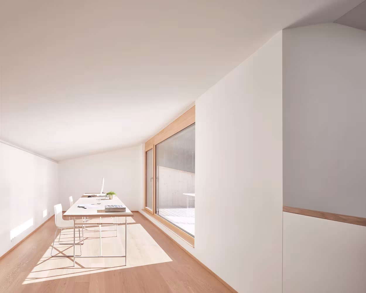 Estancia blanca con mesa de trabajo y ventanal corredero en la casa adosada de MWArchitekten en Hohenems, Austria