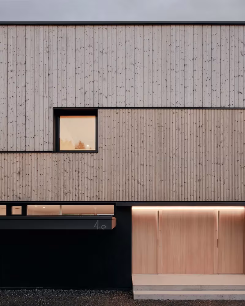 Detalle de la fachada de tablas verticales de madera con ventanas encajadas y puerta de entrada en Hohenems, Austria