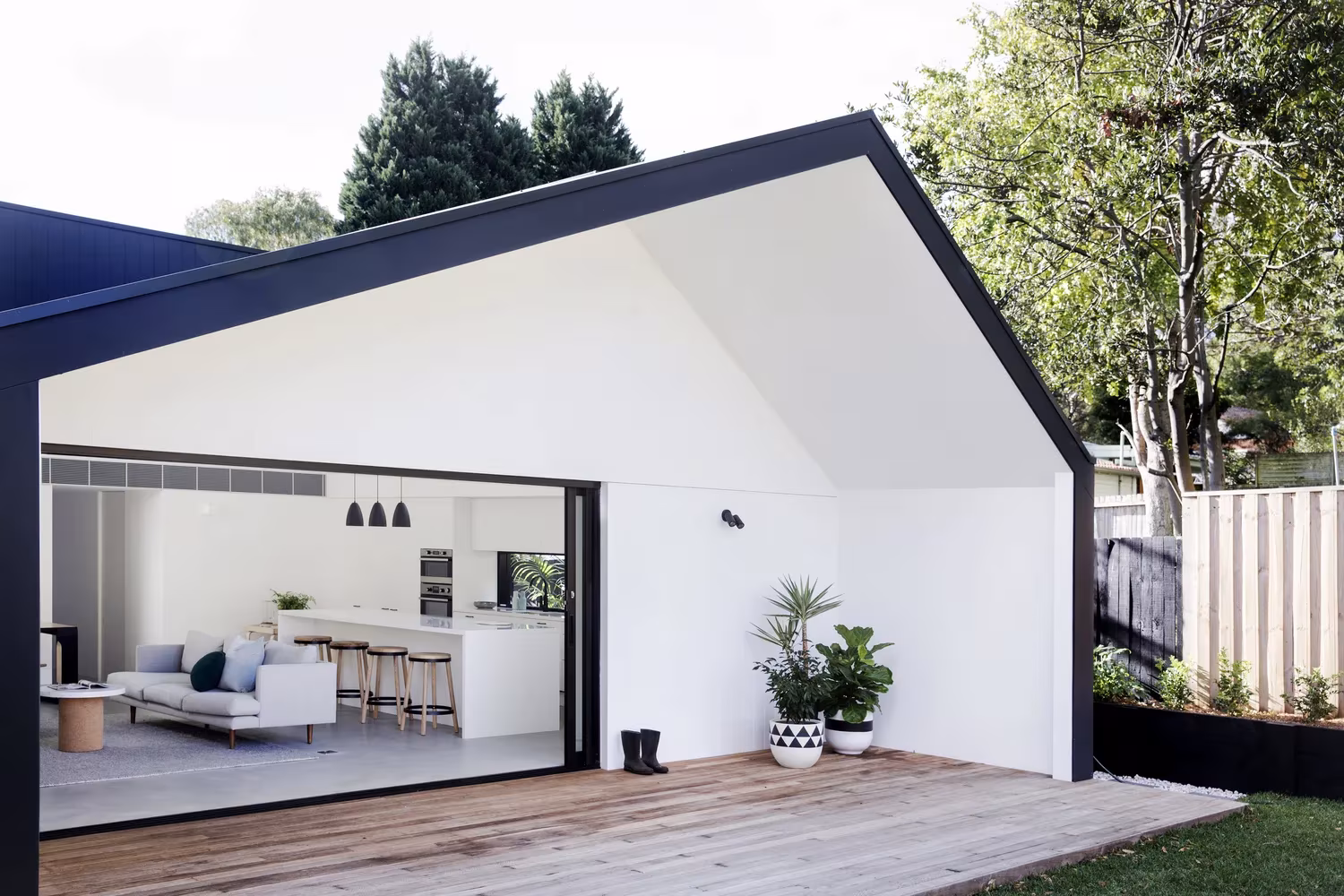 Ampliación de Studio Prineas abierta al jardín con una gran puerta corredera y terraza de madera, en Sídney