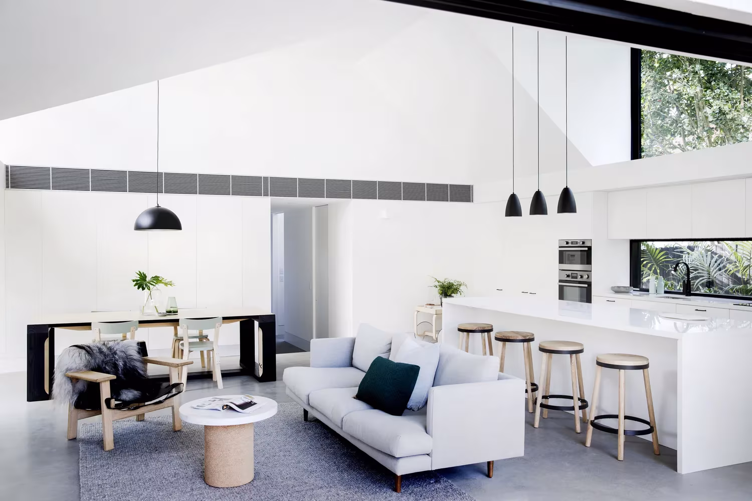 Zona de estar con sofás y mesa de comedor bajo el techo inclinado de la Allen Key House de Studio Prineas, Sídney