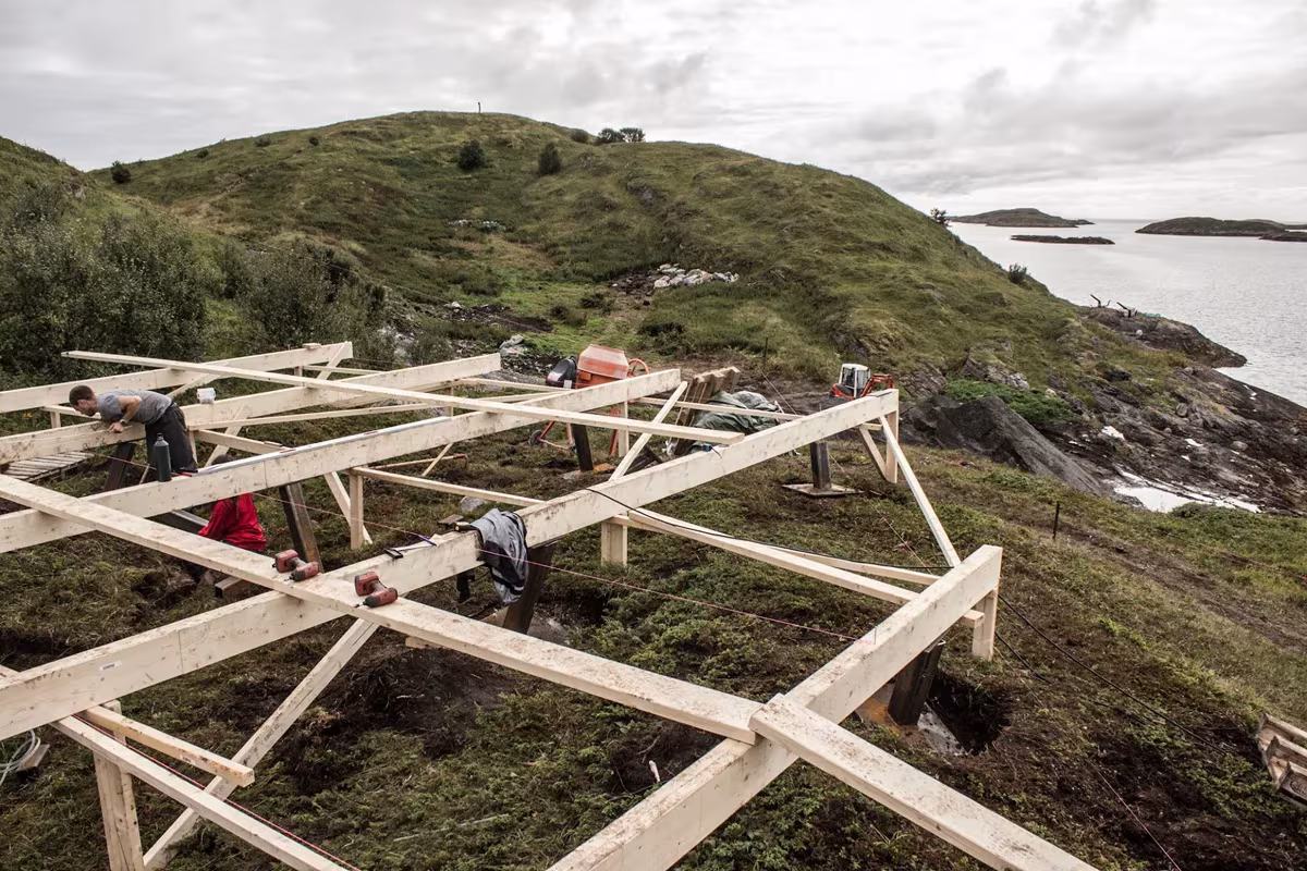 Entramado de vigas de madera que sirve de base a una cabaña de Fleinvær sobre la ladera, durante la obra
