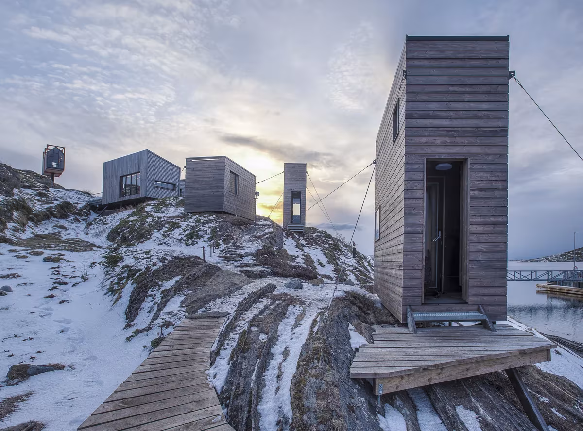 Pasarela de madera que conecta las cabañas del refugio de artistas de Fleinvær sobre la roca nevada
