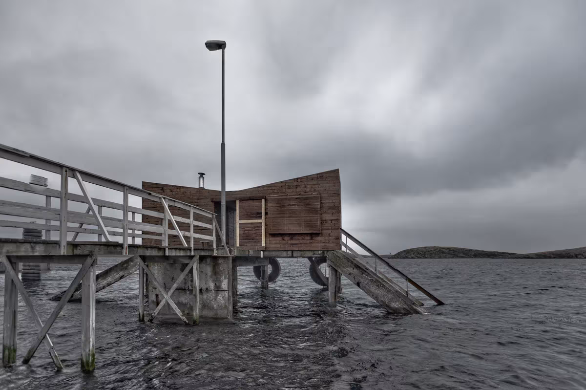 Cabaña de la sauna sobre un embarcadero de pilotes de madera junto al mar en Fleinvær, Noruega