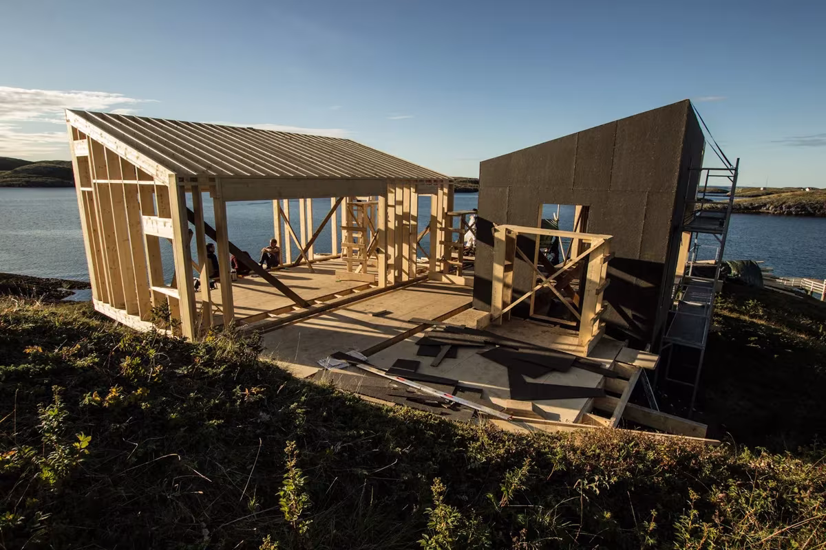 Estructura de madera en construcción de una cabaña de Fleinvær junto al mar, con cubierta metálica a medio montar