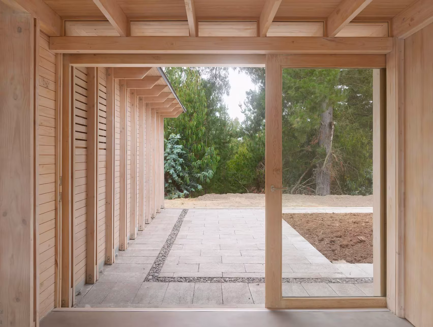 Galería de El Peumo con carpintería de madera y puerta corredera que se abre a un camino de piedra, Chile