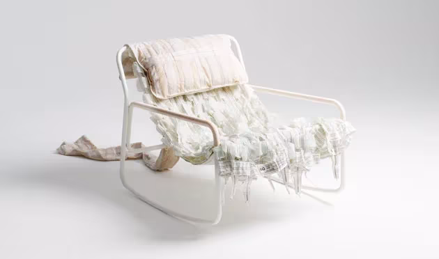 Mecedora Canopy de Layer y Raeburn con estructura blanca, asiento de tiras de tela y cojín de paracaídas reciclado