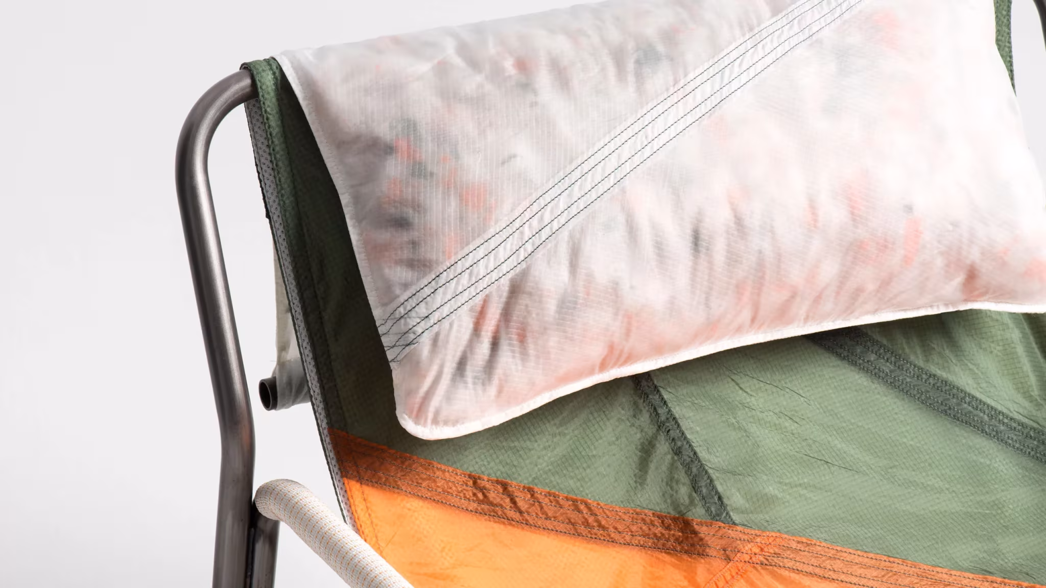 Detalle del cojín de paracaídas estampado sobre el asiento verde y naranja de una mecedora Canopy de Layer y Raeburn