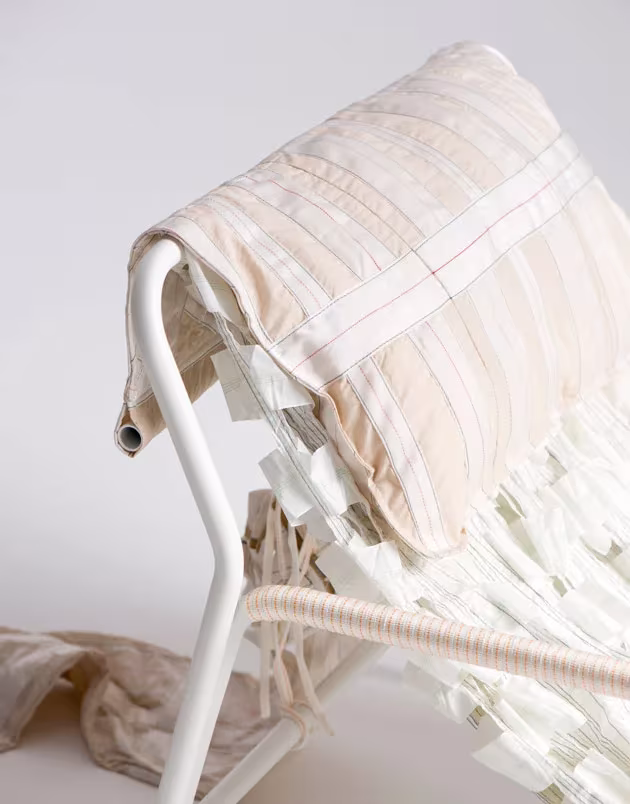 Detalle del asiento y el cojín acolchado de una mecedora Canopy de Layer y Raeburn con tiras de tela blancas