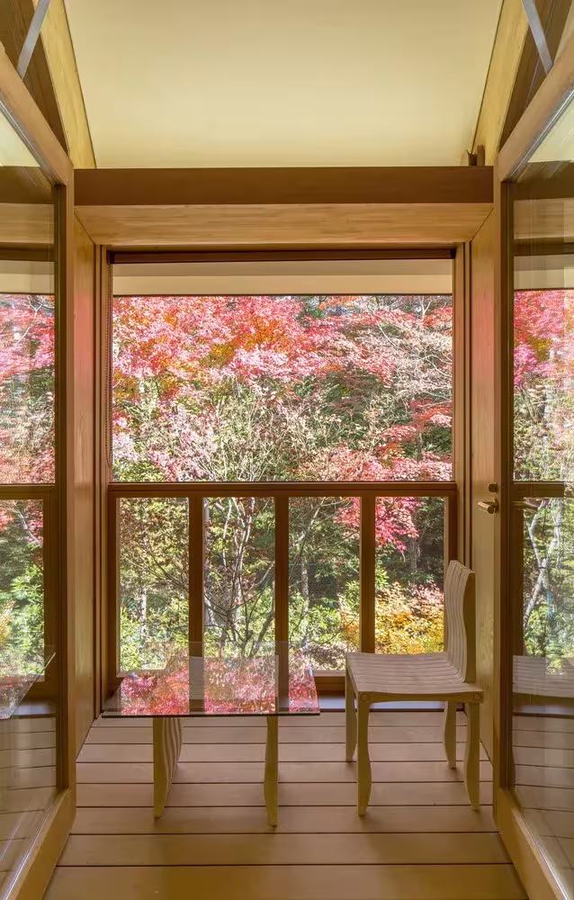 Estancia con carpintería de madera y vistas al arce rojo del jardín en el resort Shishi-iwa de Shigeru Ban, Karuizawa