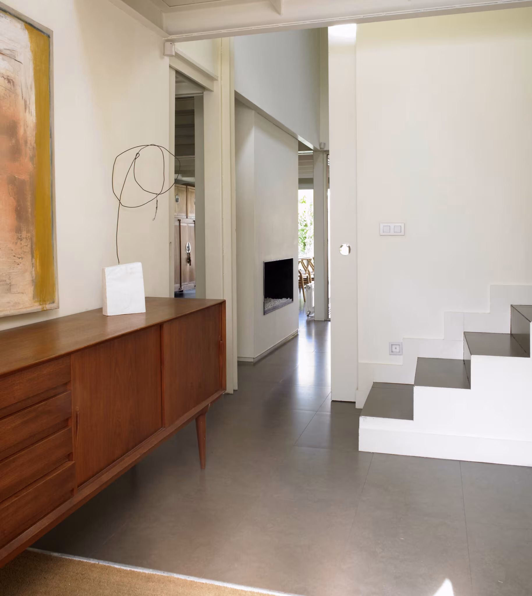 Recibidor moderno de BATAVIA con aparador de madera de mediados de siglo, cuadro abstracto y escalera blanca
