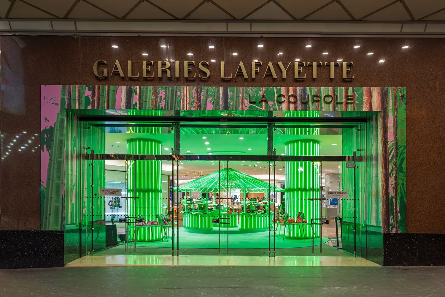 Entrada de Galeries Lafayette con el pop-up verde neón de Prada visible tras las puertas de cristal