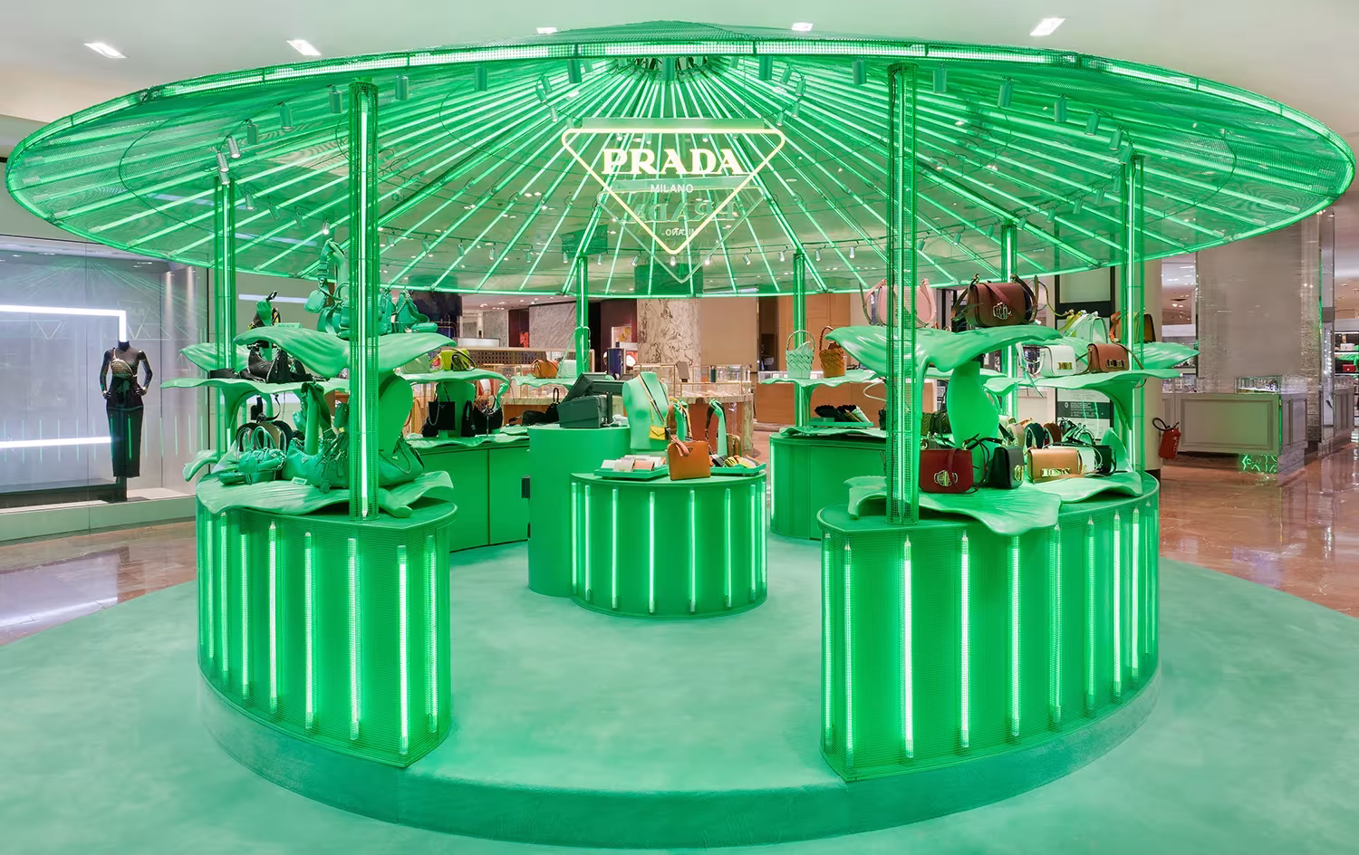 Kiosco circular de Prada con cubierta radial verde y mostradores iluminados en el pop-up Hyper Leaves de París