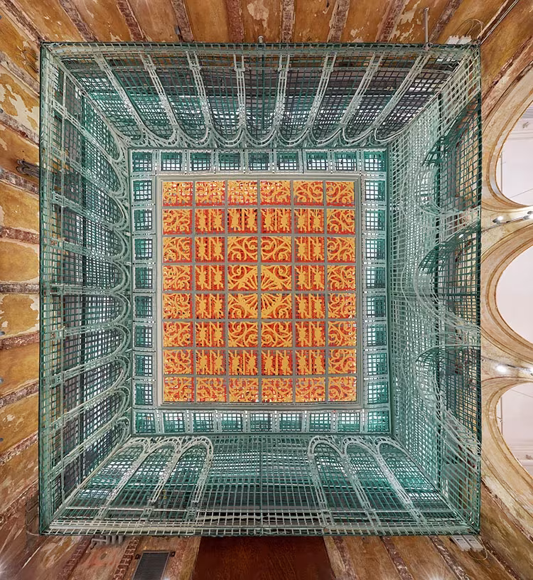 Vista cenital desde el suelo de Over View, con la trama textil verde y el panel central naranja entre muros de ladrillo