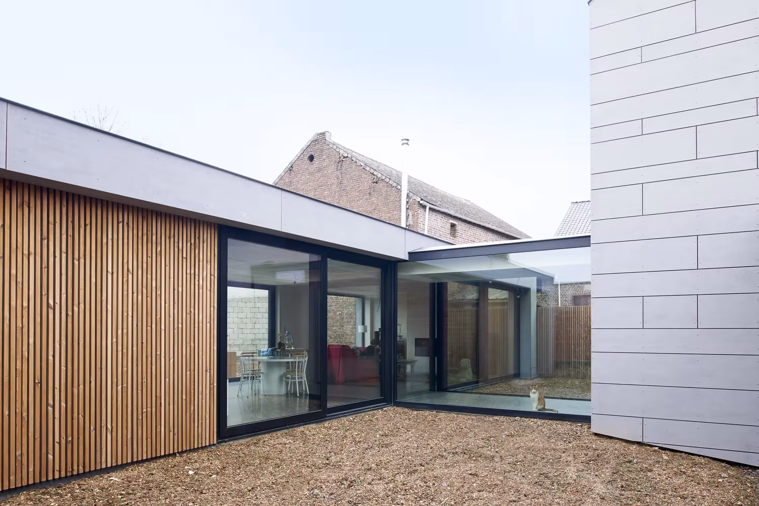 Esquina de Goetsenhoven House de AST 77 Architecten con lamas de madera, vidrio y paneles grises