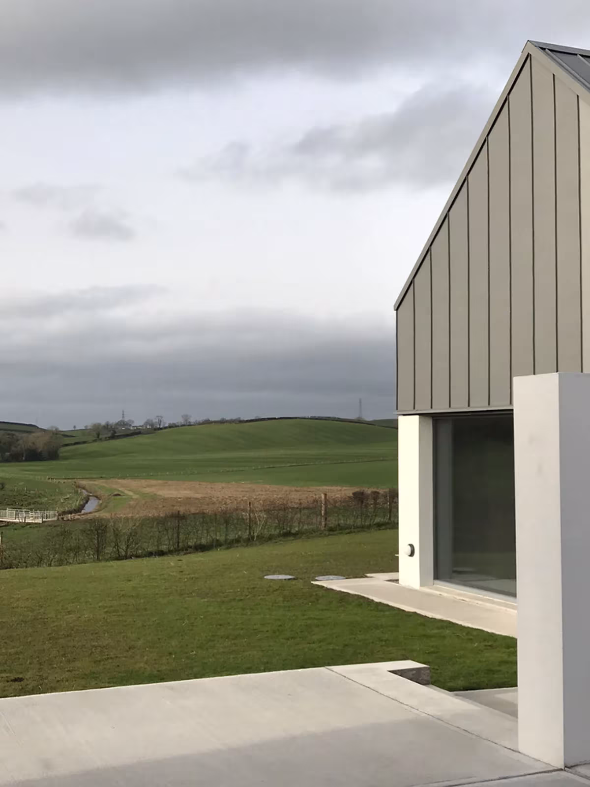 Testero de zinc y muro blanco de House Lessans abierto hacia los campos del condado de Down