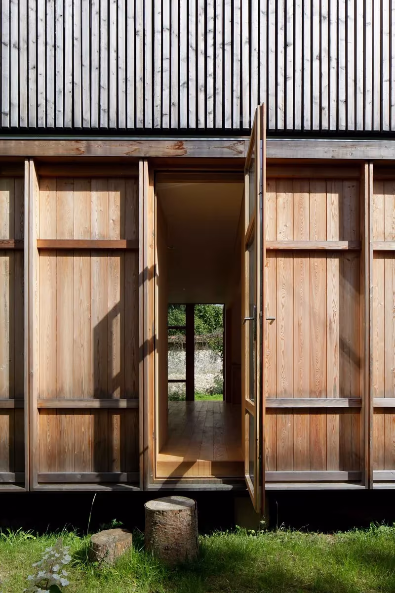 Detalle de las puertas de madera de la Maison dans le Jardin abiertas hacia el jardín y el muro vecino