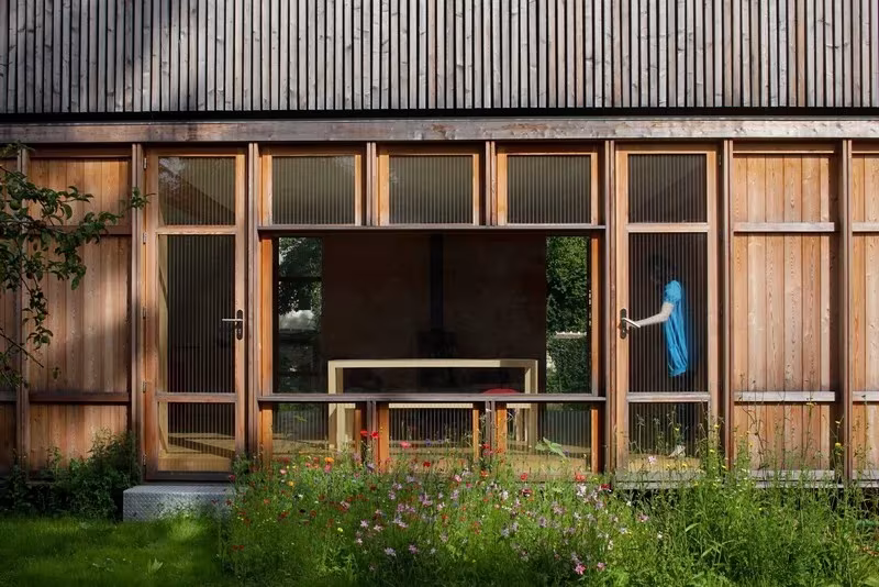Planta baja de la casa de Arba, con grandes paños de madera practicables abiertos al jardín florido