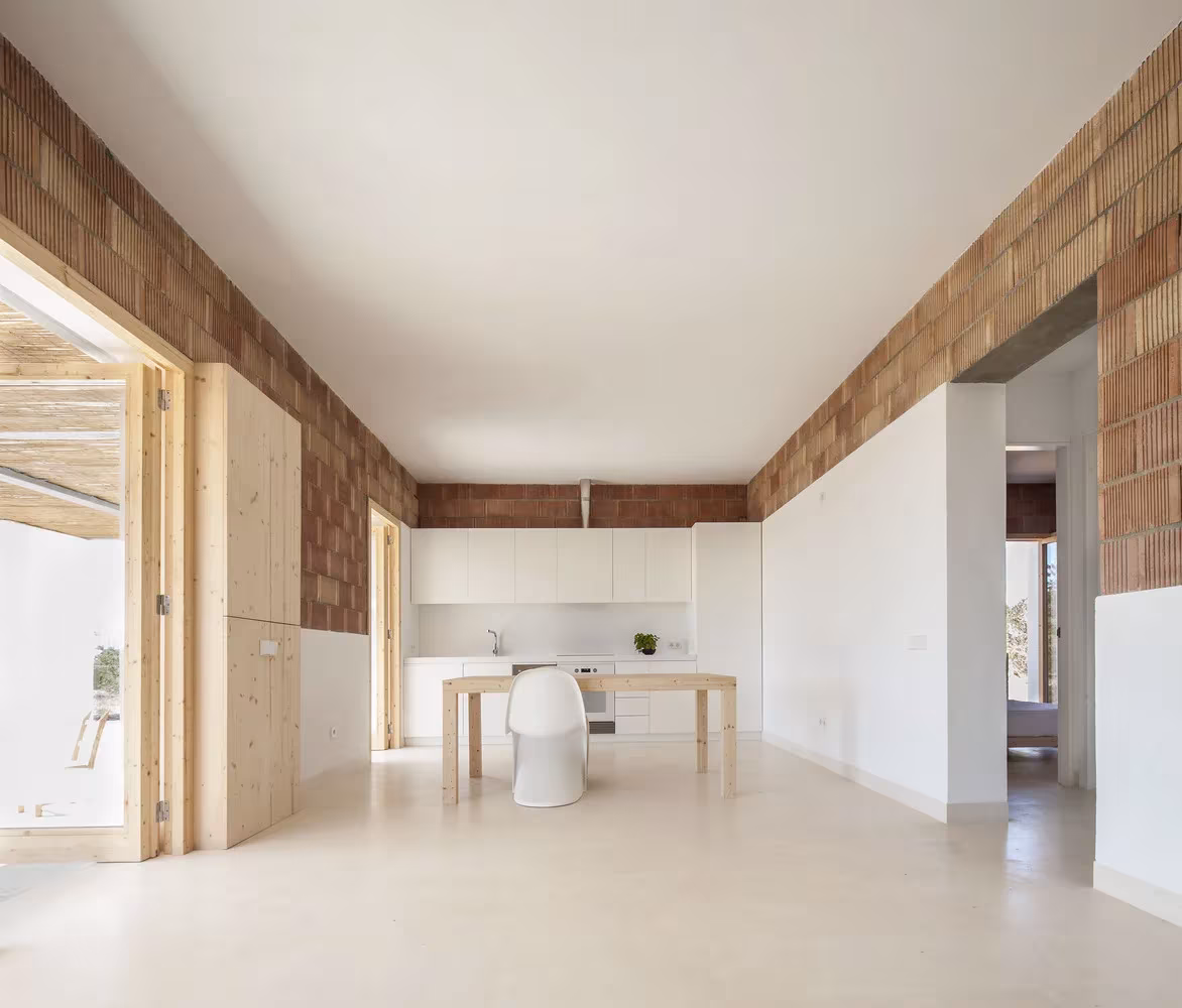 Cocina-comedor de Can Xomeu Rita, de Marià Castelló, con suelo continuo claro y paredes de ladrillo visto