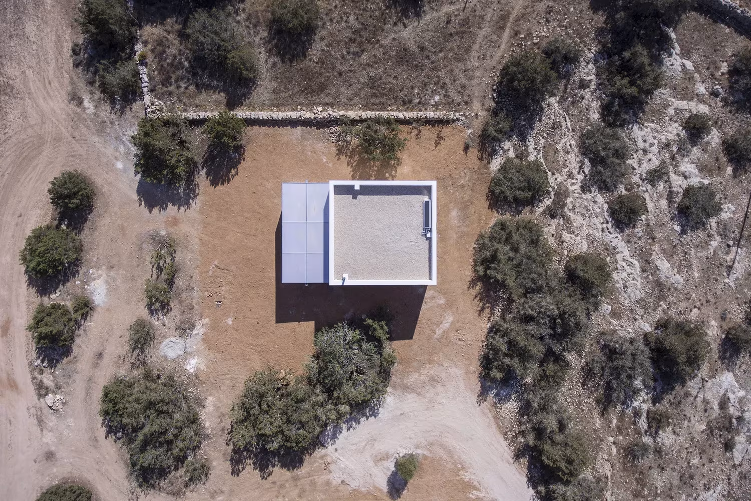 Vista aérea de Can Xomeu Rita, un volumen blanco rodeado de sabinas y tierra seca en Formentera