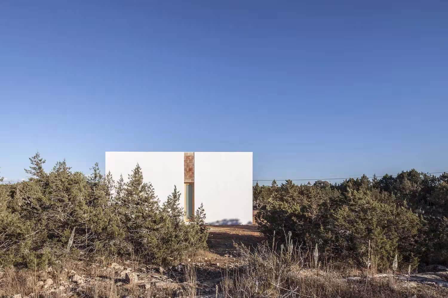 Fachada blanca de Can Xomeu Rita entre pinos y matorral bajo el cielo azul de Formentera