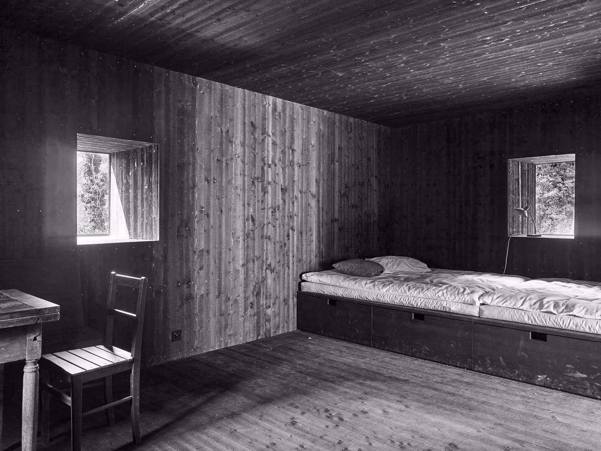 Habitación revestida de madera con cama empotrada y dos ventanas pequeñas en Casa Mosogno