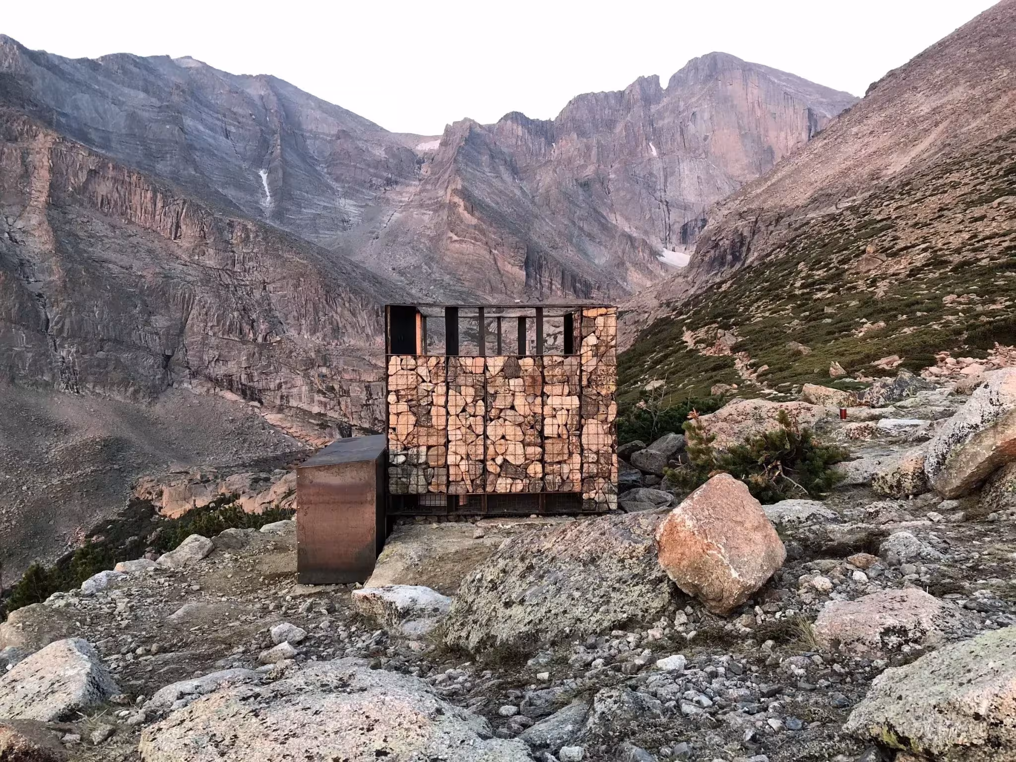 Aseo prefabricado de piedra y metal en el valle rocoso del Longs Peak con las montañas al fondo, Colorado