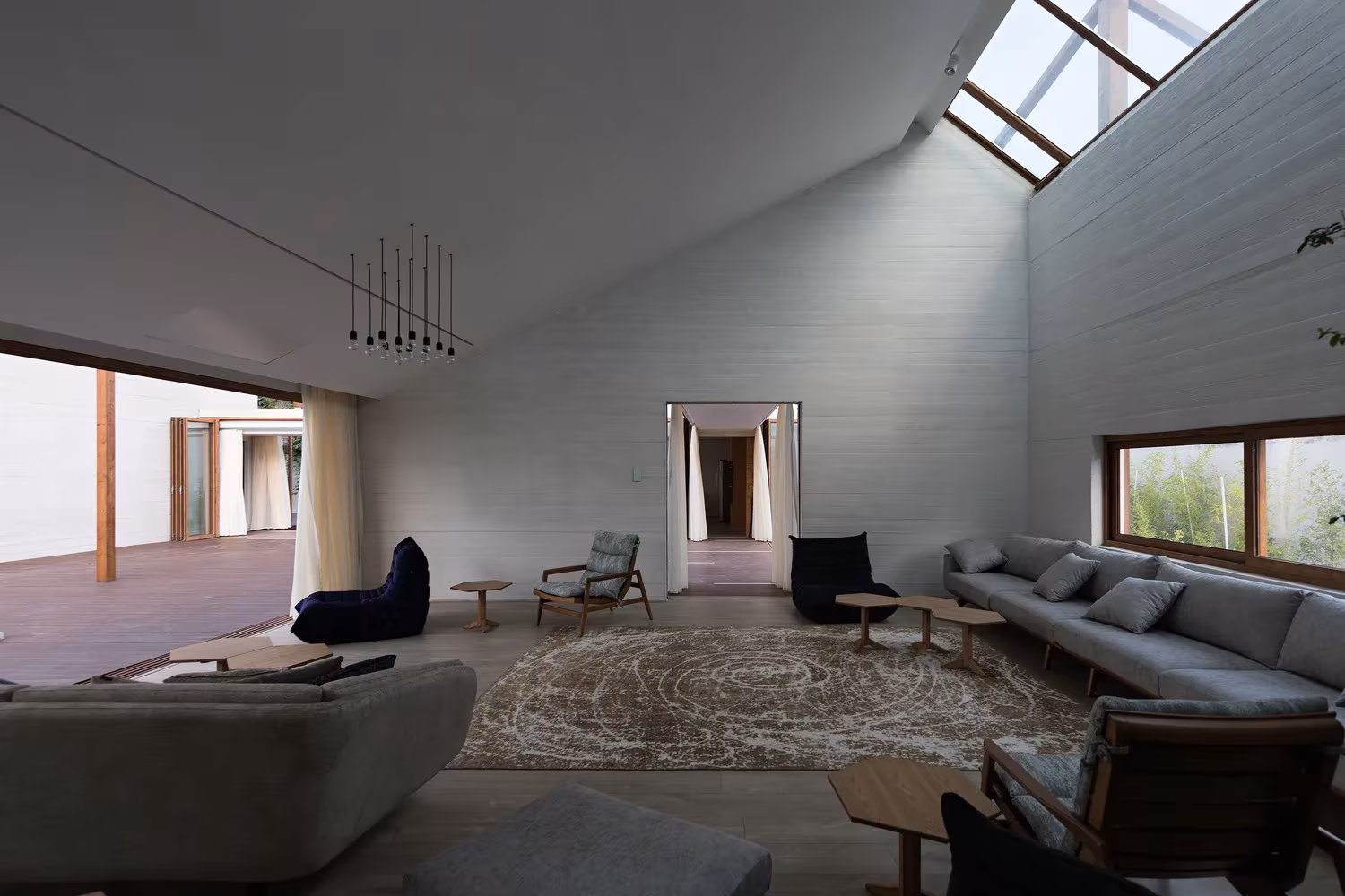 Sala de estar de Villa Vanoosh con paredes de hormigón visto, lucernarios y sofás bajo cubierta a dos aguas