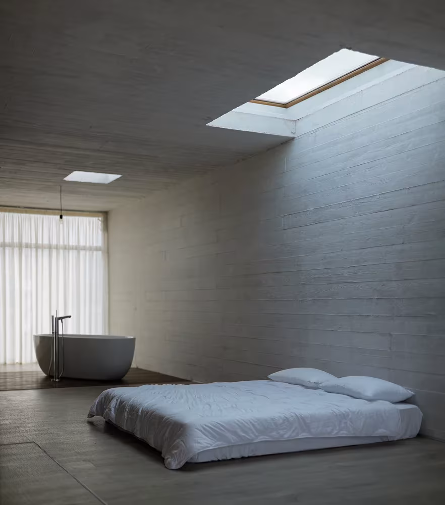 Dormitorio de hormigón visto con bañera exenta y lucernario en Villa Vanoosh, Mazandaran