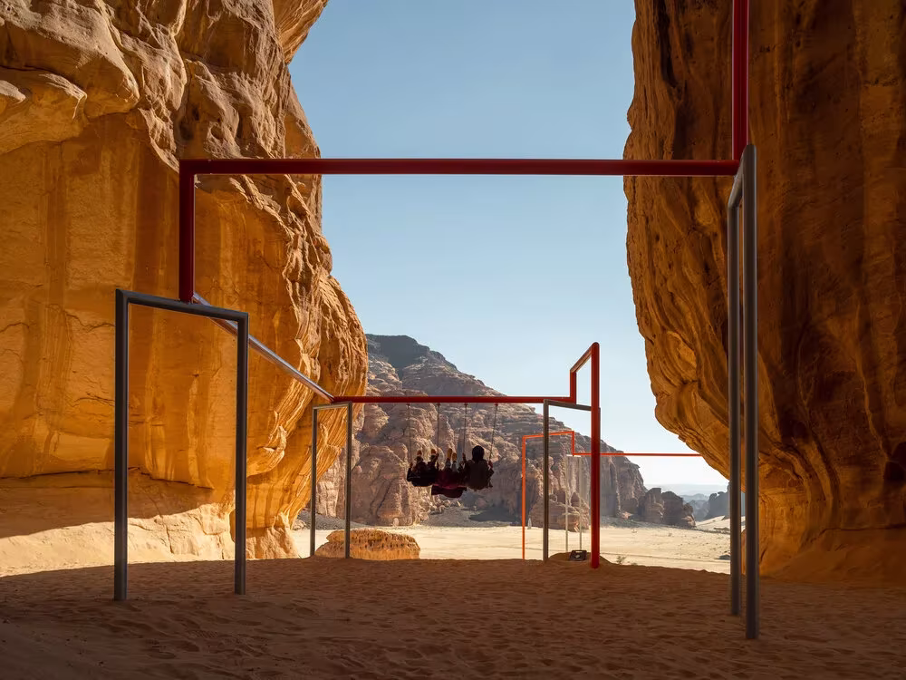 Pórtico metálico rojo con un columpio suspendido entre dos paredes de arenisca en AlUla, Desert X