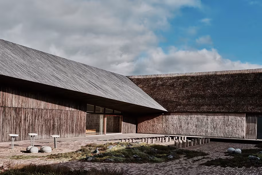 Fachadas de madera envejecida y cubiertas de paja del centro del Mar de Wadden, con rocas y brezo en el patio