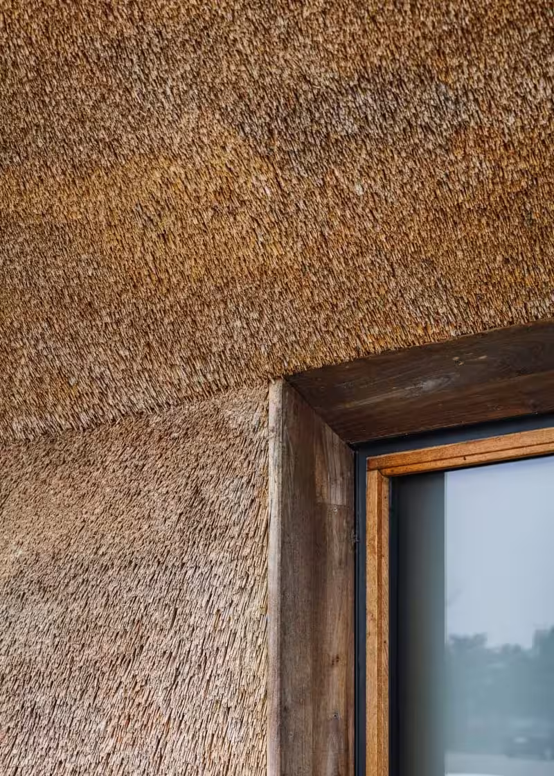 Detalle de la cubierta de paja y de una ventana con marco de madera en el centro del Mar de Wadden de Dorte Mandrup