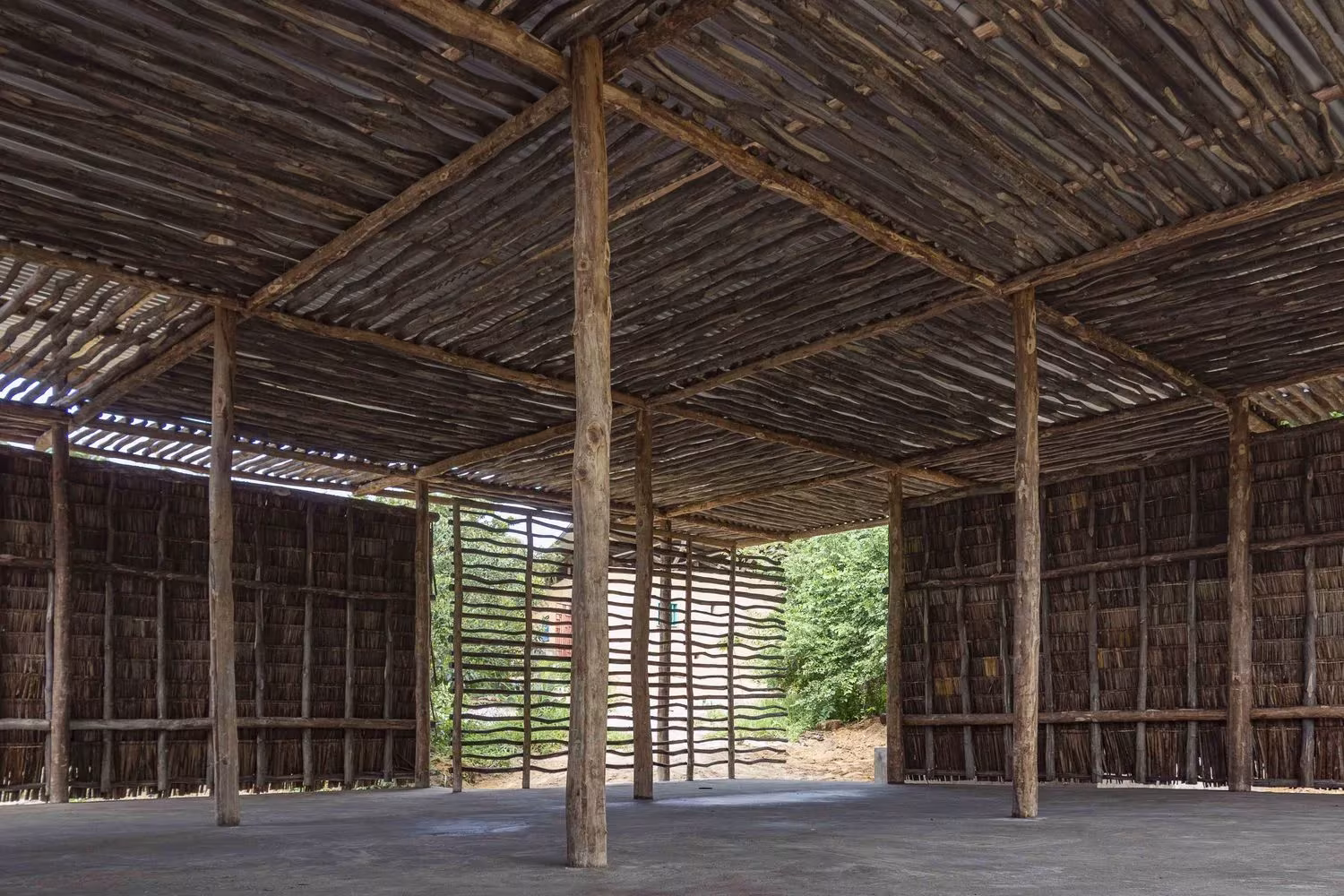 Interior diáfano del aula del Eco Moyo Education Center con cubierta de listones y muros de hojas de coco