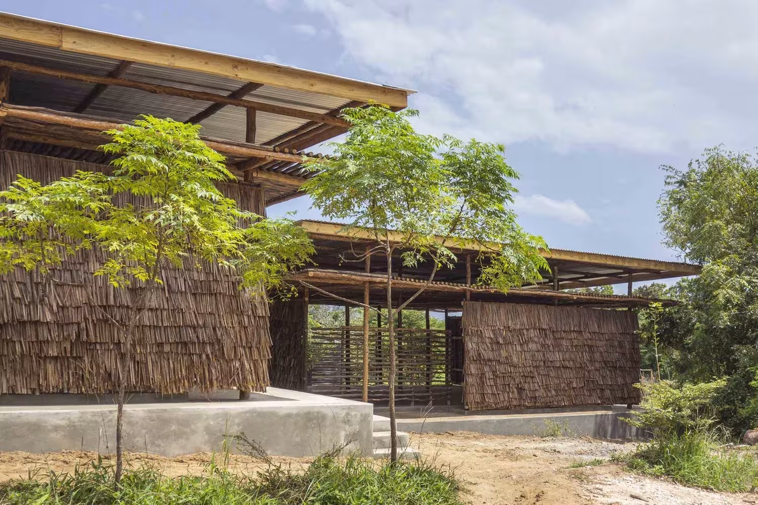 Aulas del Eco Moyo Education Center con muros de hojas de coco y cubierta de madera sobre una plataforma de hormigón